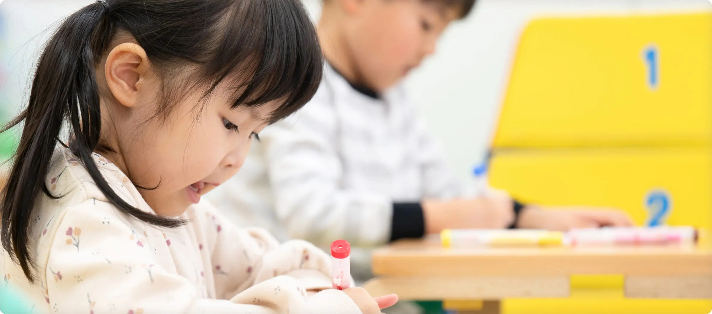 教室でお絵かきに集中する幼児