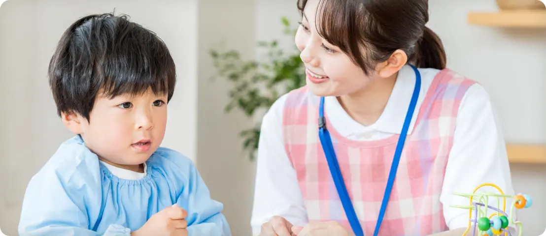 女性の指導員と幼児が話す様子